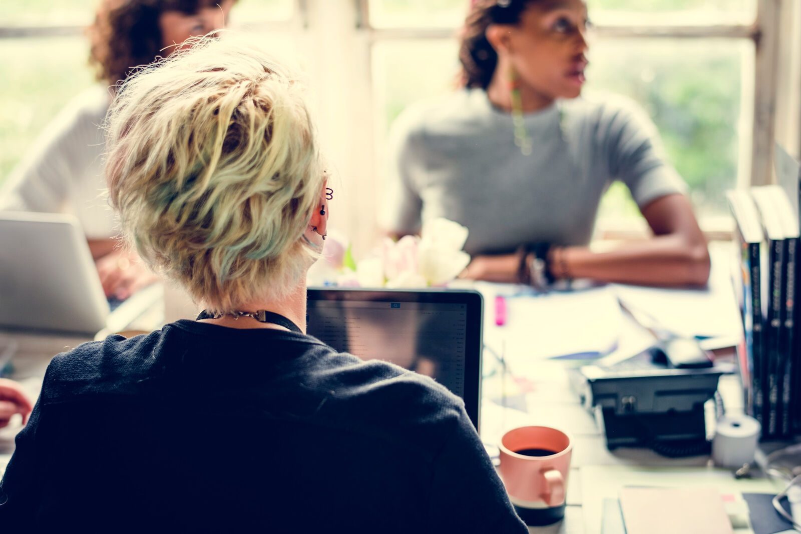 A multicultural group of women sitting at a table, talking and working together